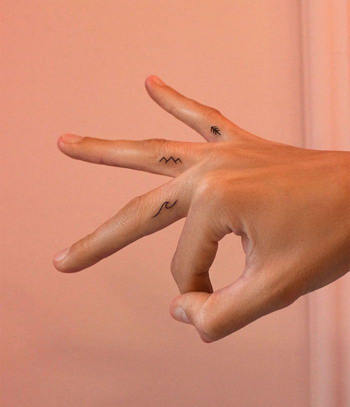 A small tattoo idea featuring minimalist symbols on fingers, including a wave, mountain peaks, and an arrow on different fingers.