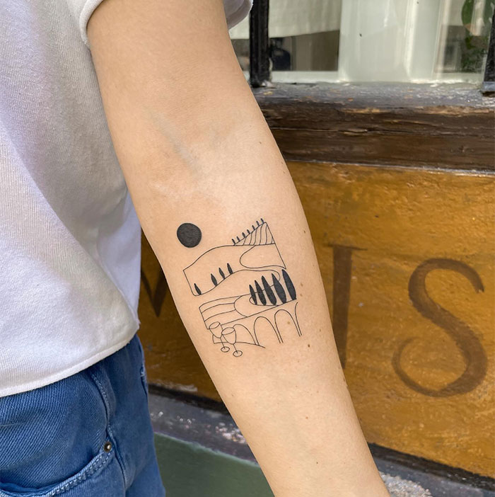 A small tattoo idea featuring a minimalist landscape with hills, trees, arches, and a sun, inked on the forearm in a simple line art style.