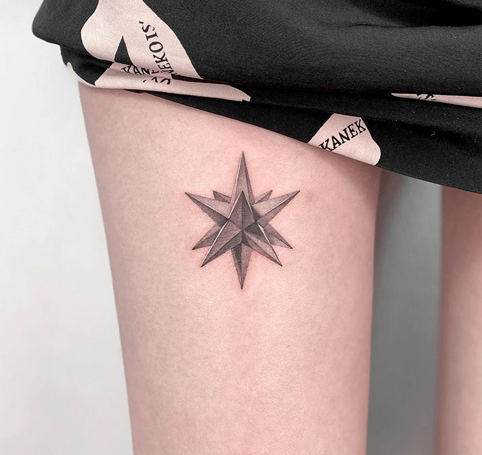 A small tattoo idea featuring a shaded, geometric star on the thigh, combining three-dimensional details with sharp, angular points for a bold effect.