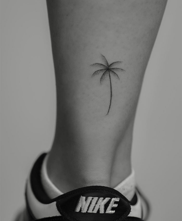 A small tattoo idea featuring a minimalist palm tree on the ankle, evoking a sense of relaxation and a tropical vibe.