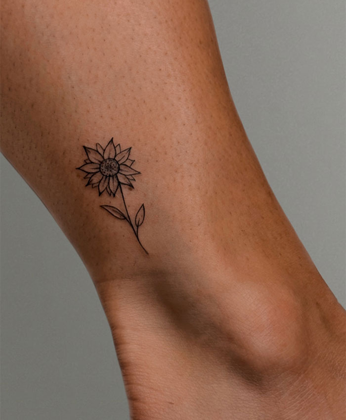 A small tattoo idea featuring a delicate sunflower on the ankle, symbolizing warmth, positivity, and joy.