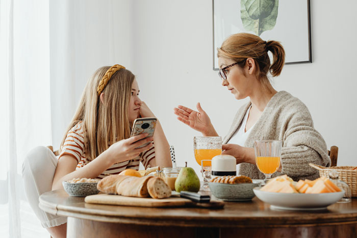 Mother and daughter having a serious conversation at the breakfast table, discussing personal issues.