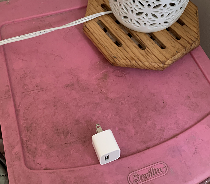 Dusty pink storage bin with a lamp on top, illustrating a filthy living space challenge for girlfriend-lives-filthy-boyfriend.