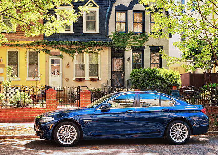 Blue car parked in driveway with neighboring houses visible, illustrating neighbor dispute.