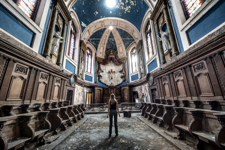 A person standing in an abandoned sacred place in Europe, surrounded by ornate architectural details.