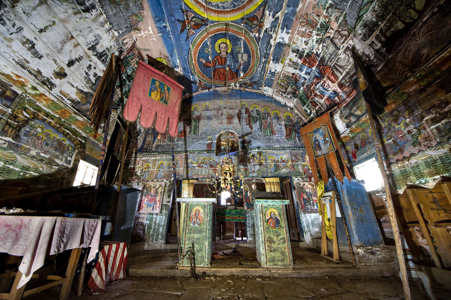 Abandoned European sacred place with colorful frescoes and worn altar, showcasing its historical beauty.