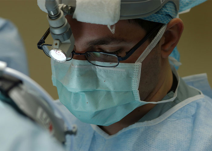 Surgeon with glasses and mask, focusing during a medical procedure, illustrating intriguing facts in healthcare.