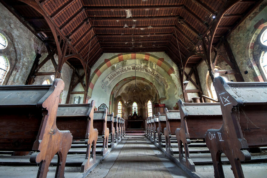 Abandoned sacred place in Europe with wooden pews and arched ceiling, showcasing historical architecture.