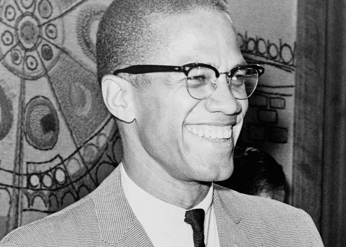 Smiling man in glasses and suit, vibrant background, intriguing facts theme.