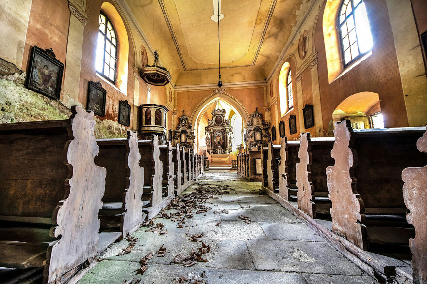 Abandoned sacred place in Europe, featuring an empty church with ornate architecture and scattered leaves on the floor.