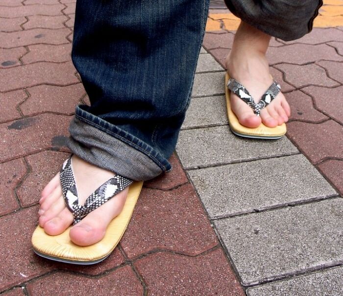 Feet wearing sandals on a brick sidewalk, capturing a casual moment related to the funniest joke theme.