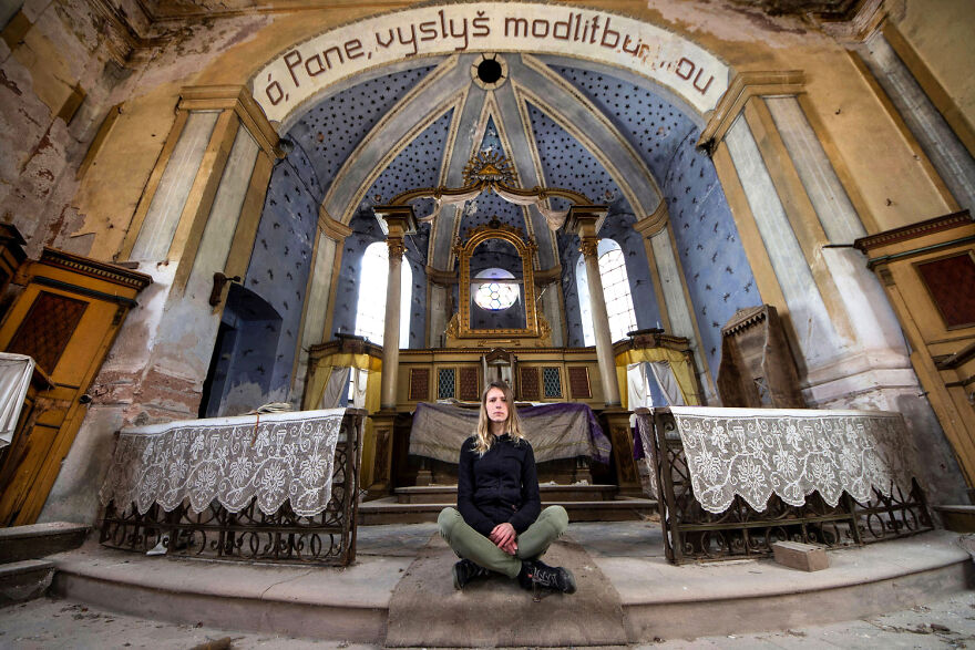 Woman sitting in an abandoned sacred place in Europe, surrounded by ornate, weathered architecture and intricate details.