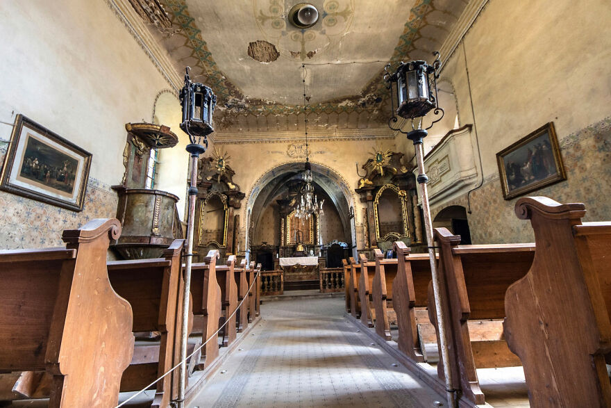 Abandoned sacred place in Europe with wooden pews and ornate altar, showcasing beautiful decay and historical architecture.