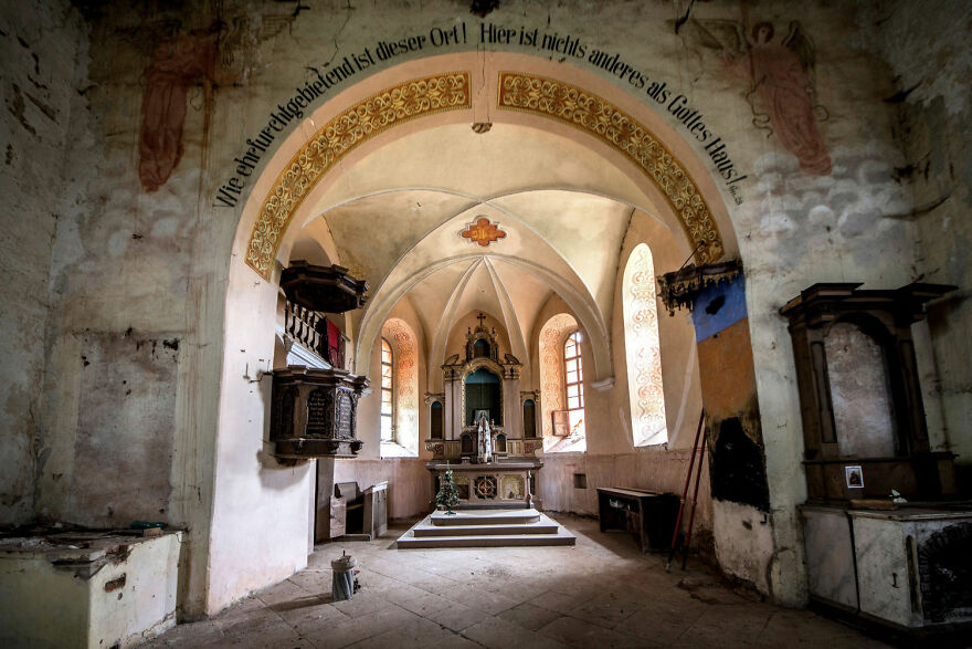 Abandoned sacred place in Europe, featuring a weathered church interior with arched ceiling and ornate altar.