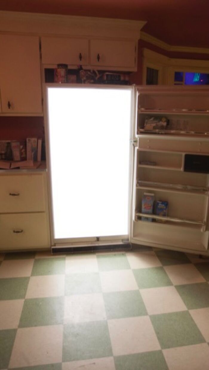 Open fridge with bright light, minimal items inside, showcasing a typical "dude fridge" scene.