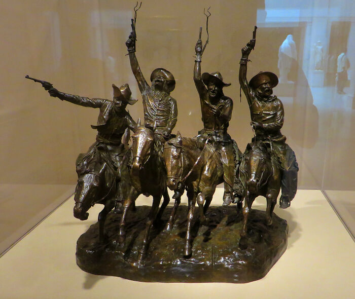 Bronze sculpture of cowboys on horseback in a luxurious home display.