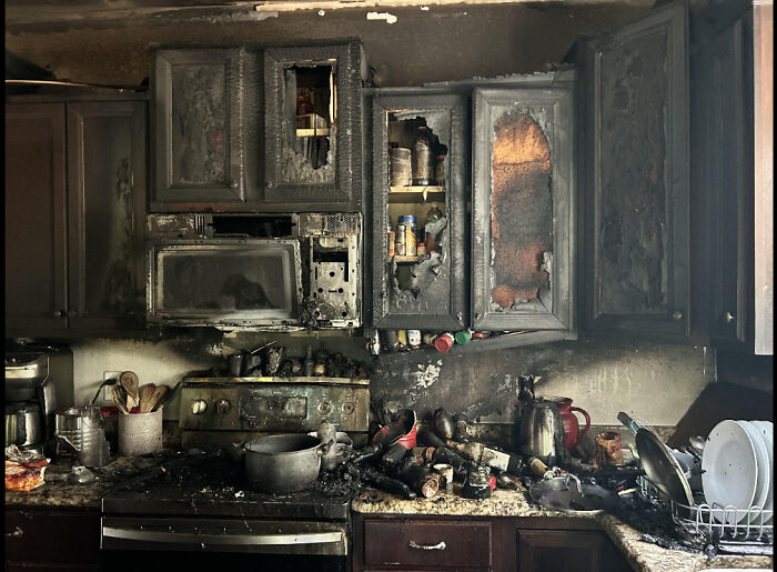 Charred kitchen resembling Renaissance painting, with burnt cabinets and scattered kitchenware.