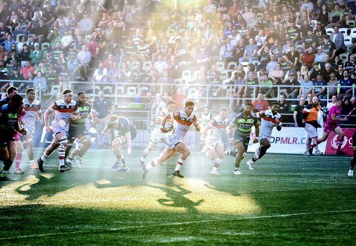 Rugby players in action, captured with dramatic lighting resembling a Renaissance painting.