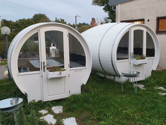 Unique building conversion featuring two barrel-shaped structures with glass doors, set outdoors on grass.