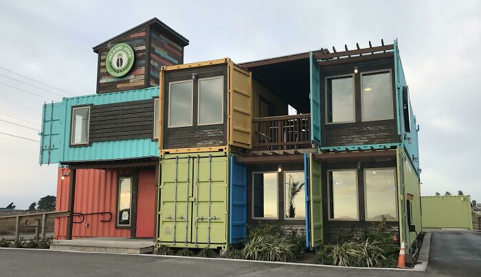 Building conversion using colorful shipping containers with modern windows and a small balcony.