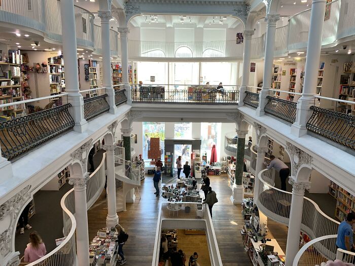 Interior of a grand building conversion into a bookstore, featuring multiple levels and intricate architectural details.