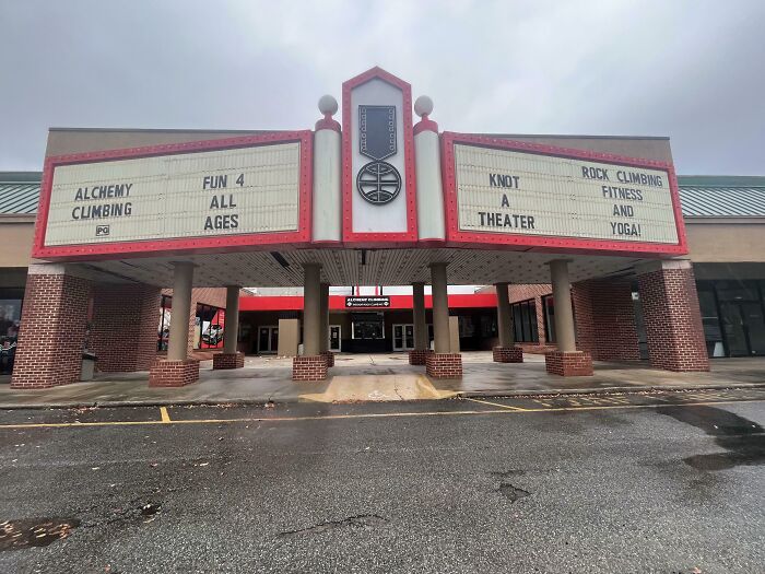 Former theater converted into a rock climbing gym, showcasing building conversions with signs for fitness and yoga.