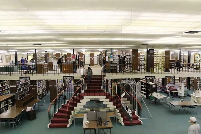 Library interior showcasing a grand staircase, highlighting one of the best building conversions with modern book displays.