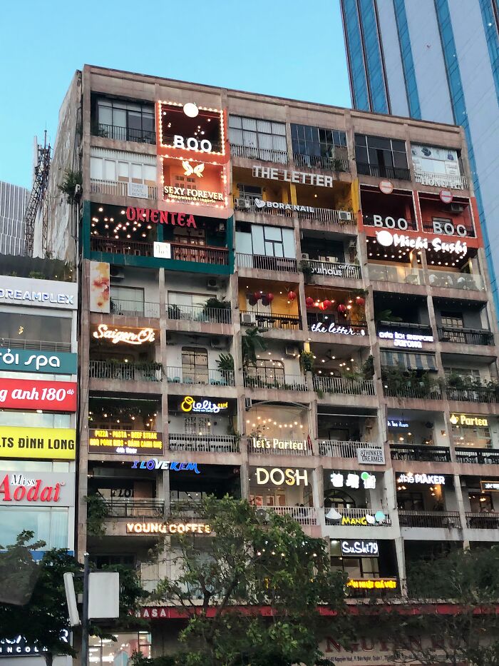 Building conversion with vibrant signage, showcasing various cafes and shops, illustrating one of the best urban transformations.