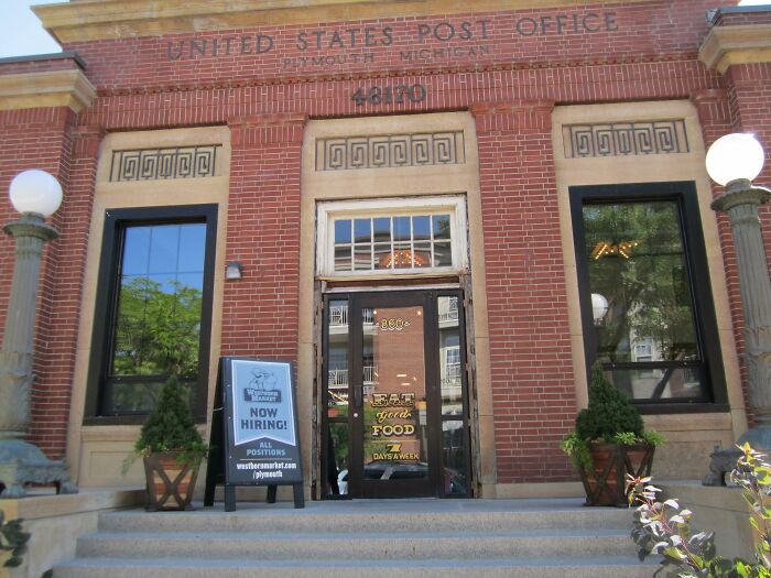 Historic post office building converted to a restaurant, featuring a hiring sign and decorative entrance.