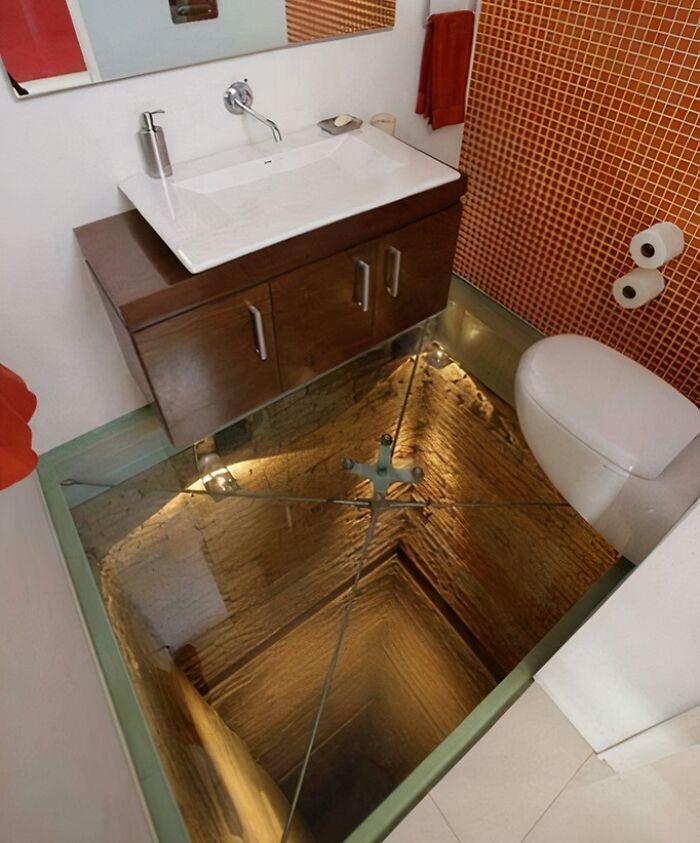 Bathroom with glass floor revealing a deep shaft, showcasing innovative building conversions.