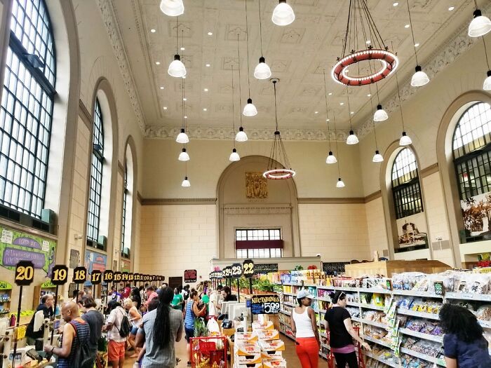 Interior of a grocery store inside a converted historic building, featuring high ceilings and hanging lights.