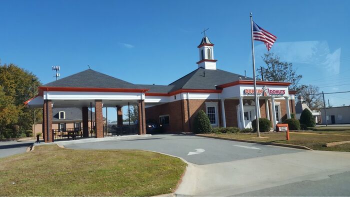 Dunkin' Donuts in a former bank building, showcasing a unique building conversion with a drive-thru and U.S. flag.