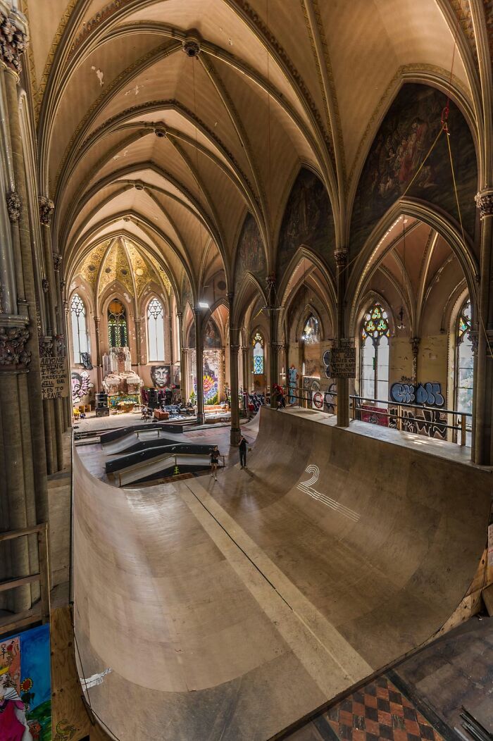 Skatepark inside a converted church with gothic arches and colorful graffiti, showcasing unique building conversion.