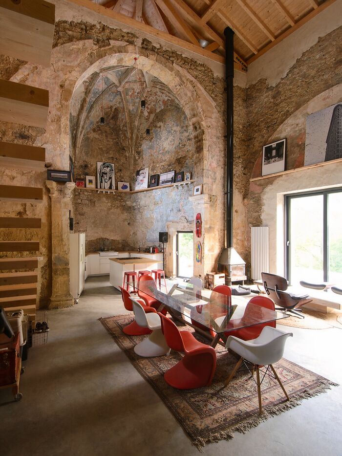 Modern dining area inside a rustic building conversion with high ceilings and eclectic decor.