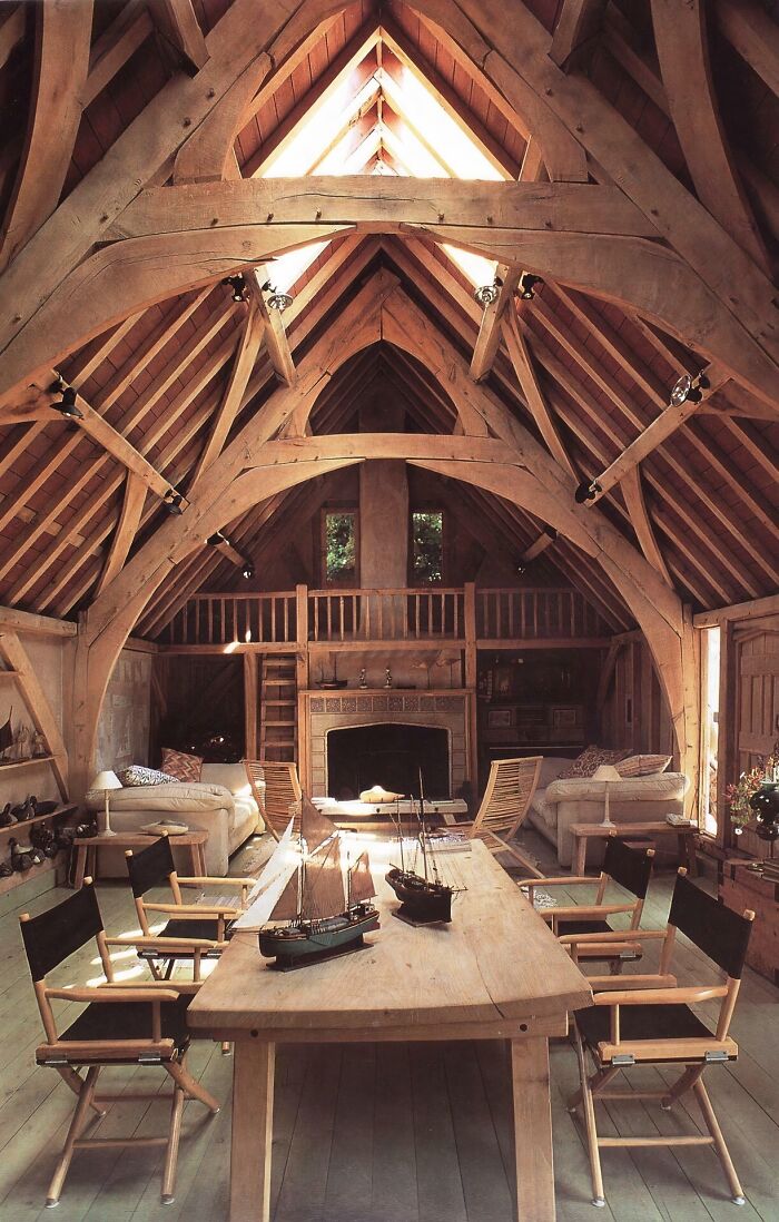 Rustic interior of a converted building featuring wooden beams, cozy seating, and a model ship on a wooden table.