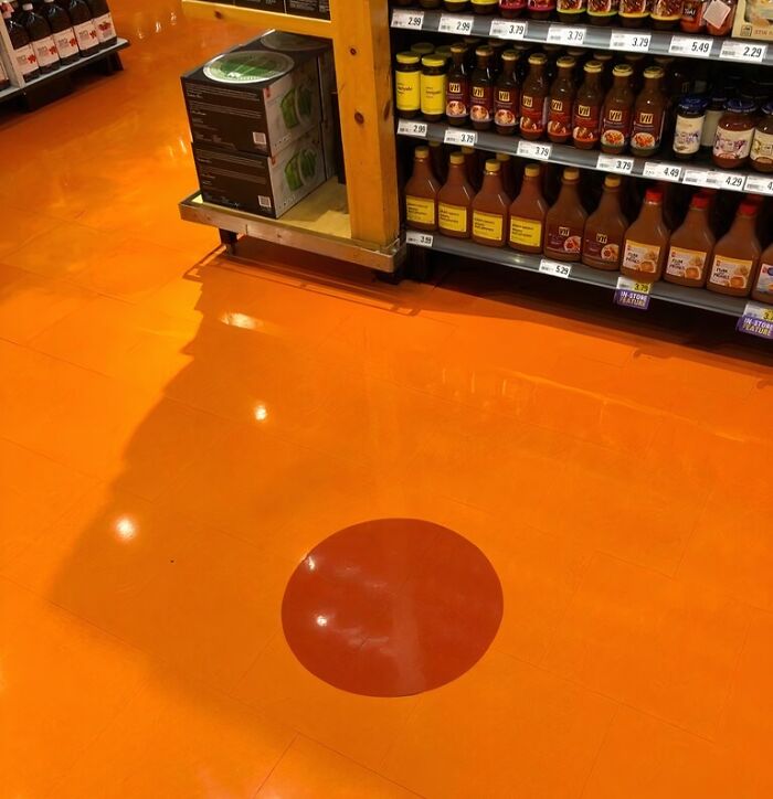 Orange supermarket floor with a red circle near shelves.