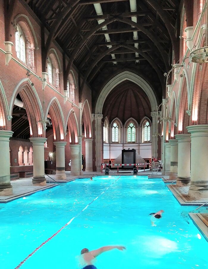 Swimming pool inside a converted building with gothic arches, showcasing unique building conversions.