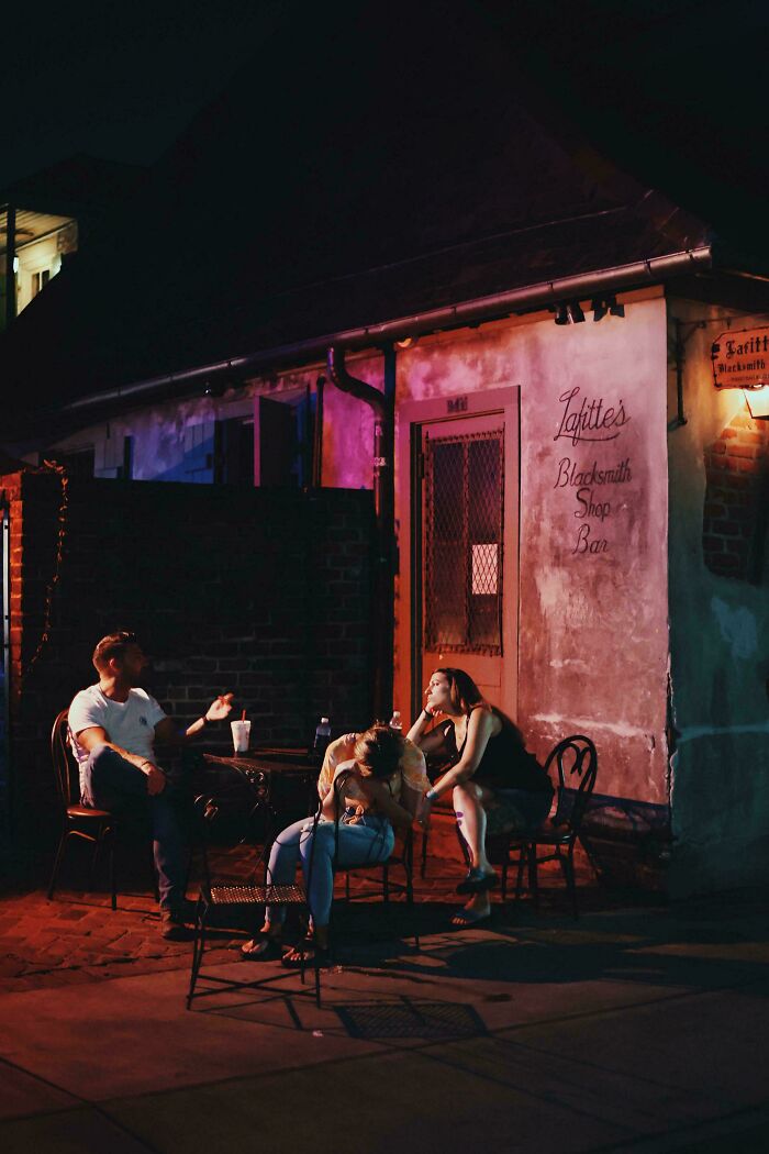 People sitting outside a bar at night, resembling a Renaissance painting with dramatic lighting and composition.