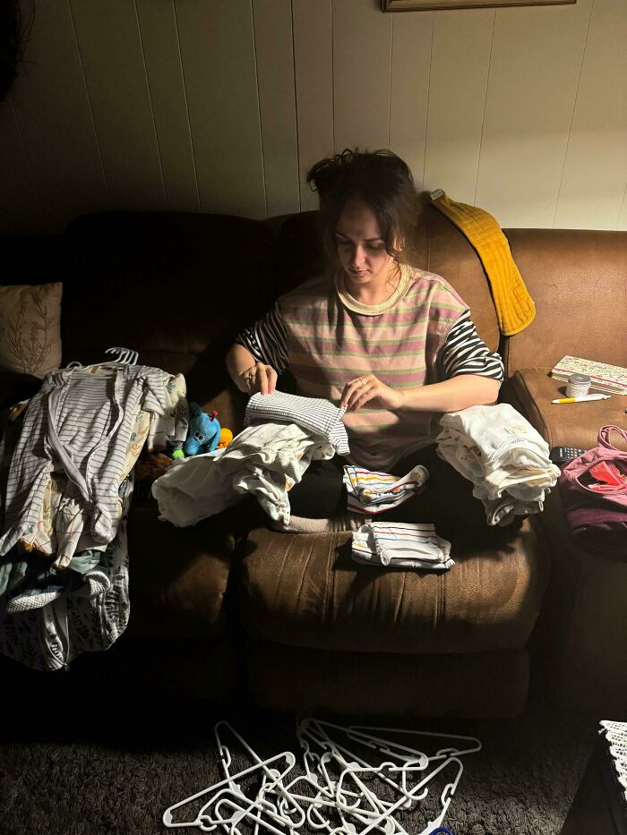 A woman folding clothes on a couch, evoking a Renaissance painting with its composition and lighting.