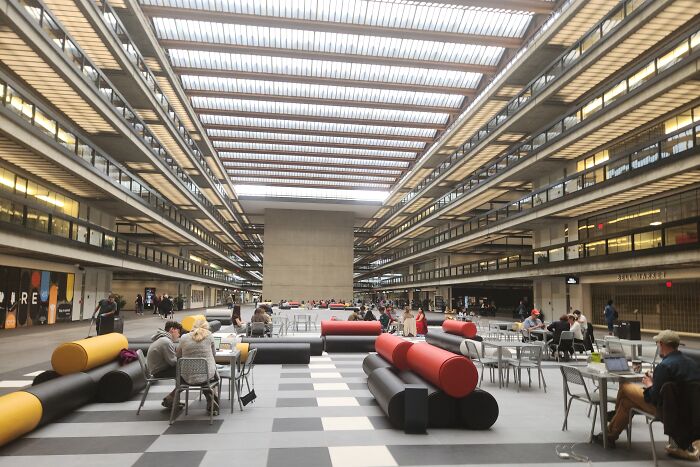 Modern building conversion with open seating area and skylight, featuring colorful benches and people working or relaxing.