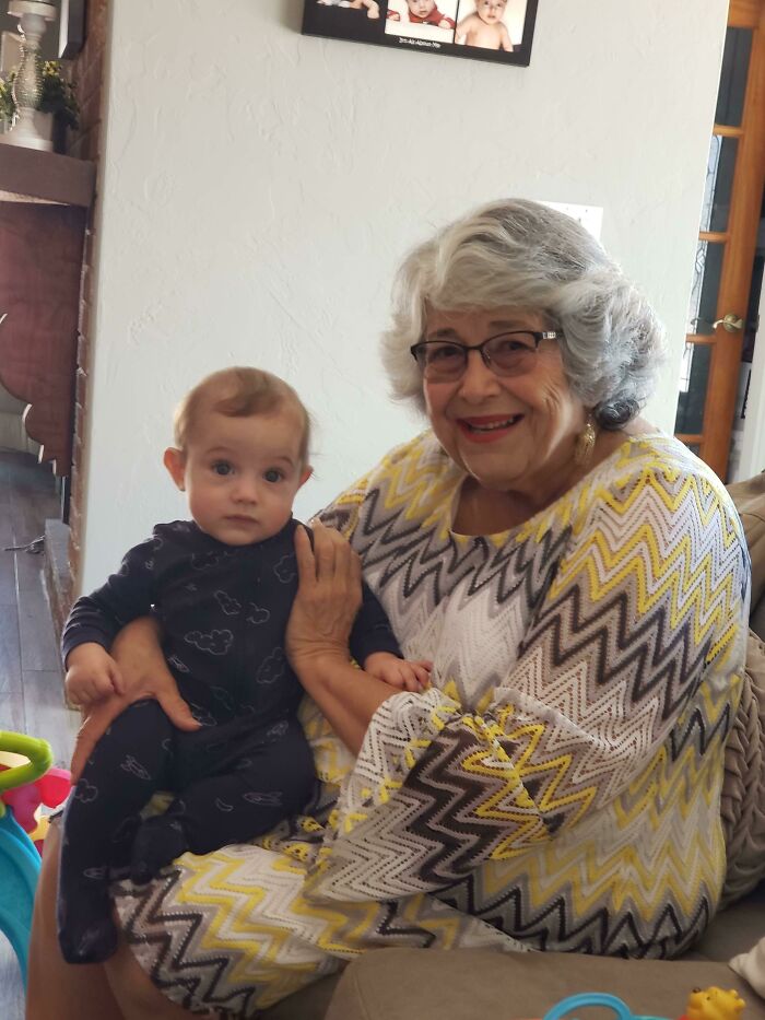 Grandmother hugging an adopted baby inside a cozy living room, showcasing a heartwarming adoption moment.