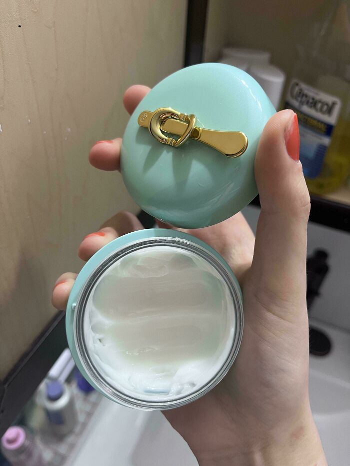 Hand holding opened cream jar with upside-down lid, showcasing typical boyfriend annoyance.