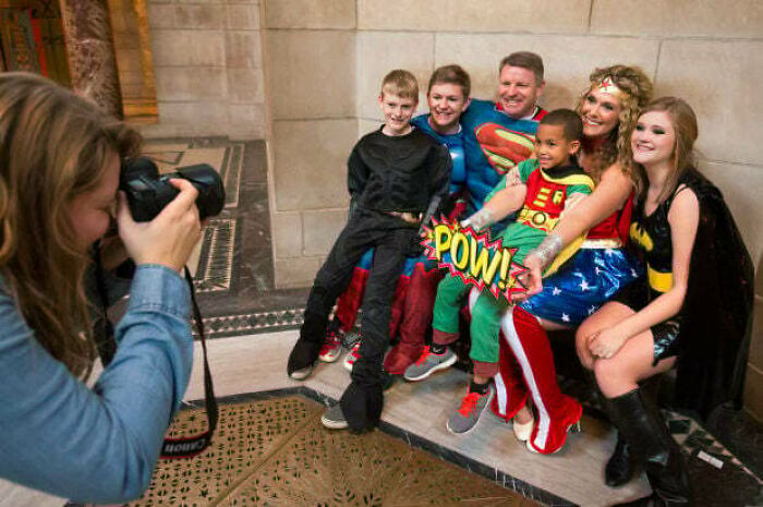 Family in superhero costumes posing for a photo, capturing a joyful moment from wholesome adoption stories.