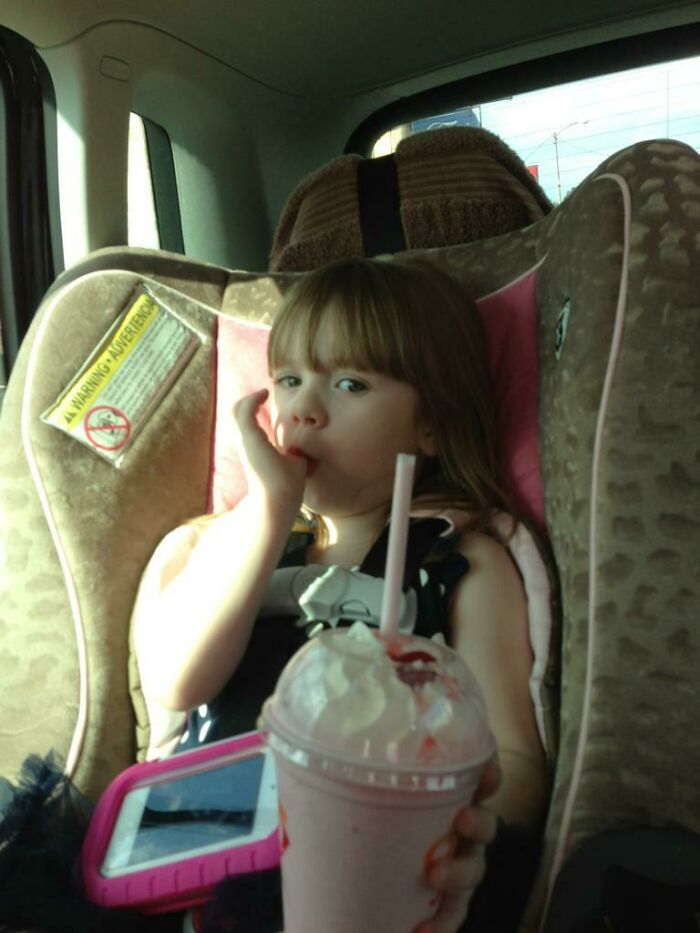 Child in a car seat enjoying a milkshake, embodying a heartwarming adoption story moment.