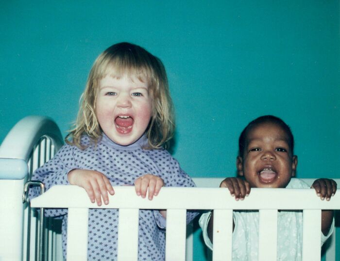 Two smiling children in a crib, celebrating a joyful moment in an adoption story.