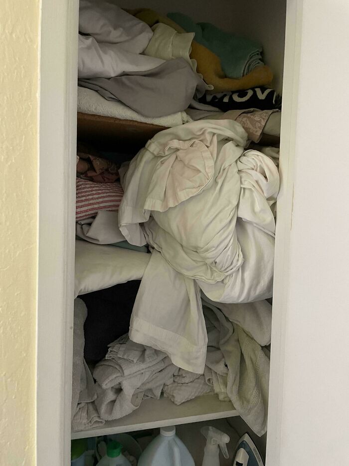 Messy linen closet with poorly folded sheets, highlighting common boyfriend household habits.