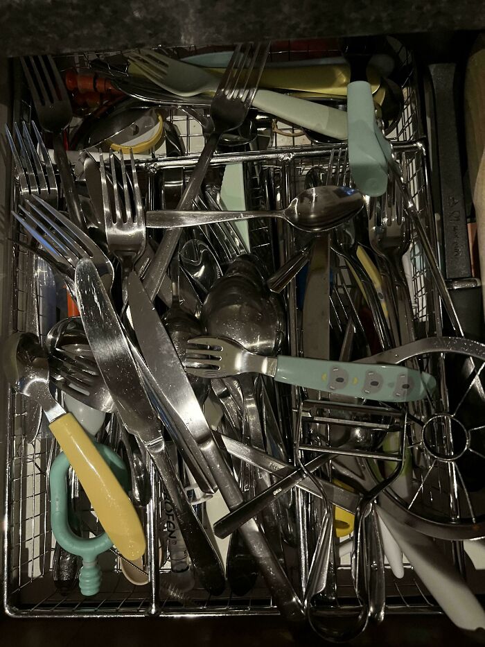 A chaotic pile of utensils crammed in a dishwasher, illustrating infuriating behavior by boyfriends or husbands.