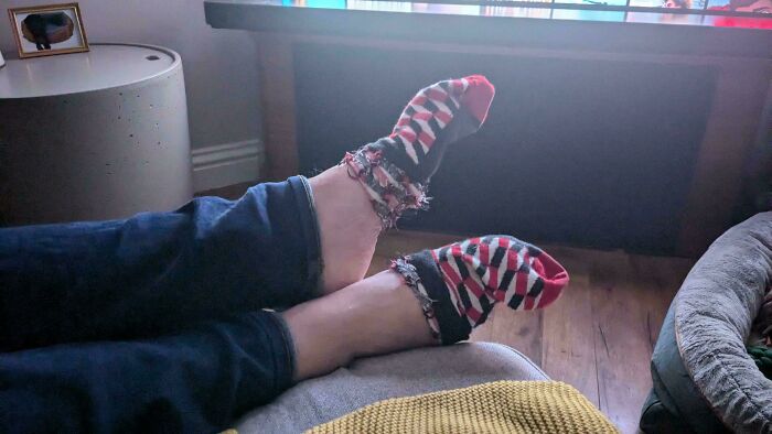 Feet in tattered socks resting on a couch, showcasing a common boyfriend annoyance at home.