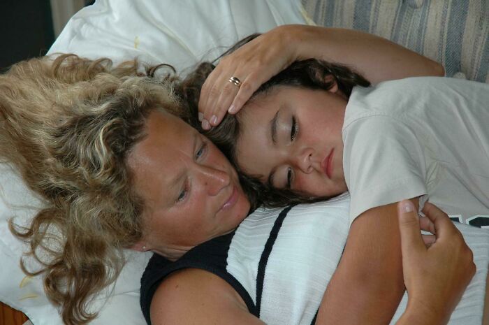 A woman lovingly cuddles a sleeping child, illustrating a wholesome adoption moment.