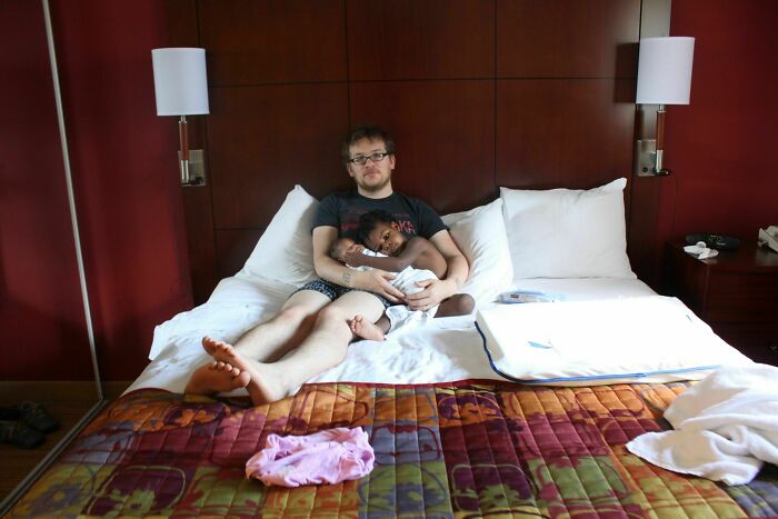 Father and adopted child sharing a loving moment on a bed, highlighting wholesome adoption stories.